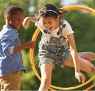 two children playing, one is jumping through a hoola hoop
