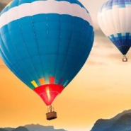 two hot air balloons flying in a sunset sky